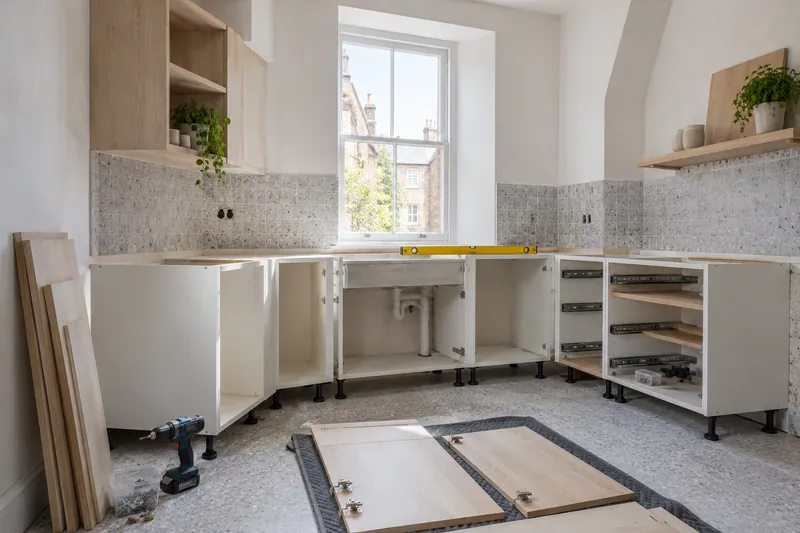 Visualización conceptual IA: Módulos de cocina en montaje con puertas pendientes de colocar.
